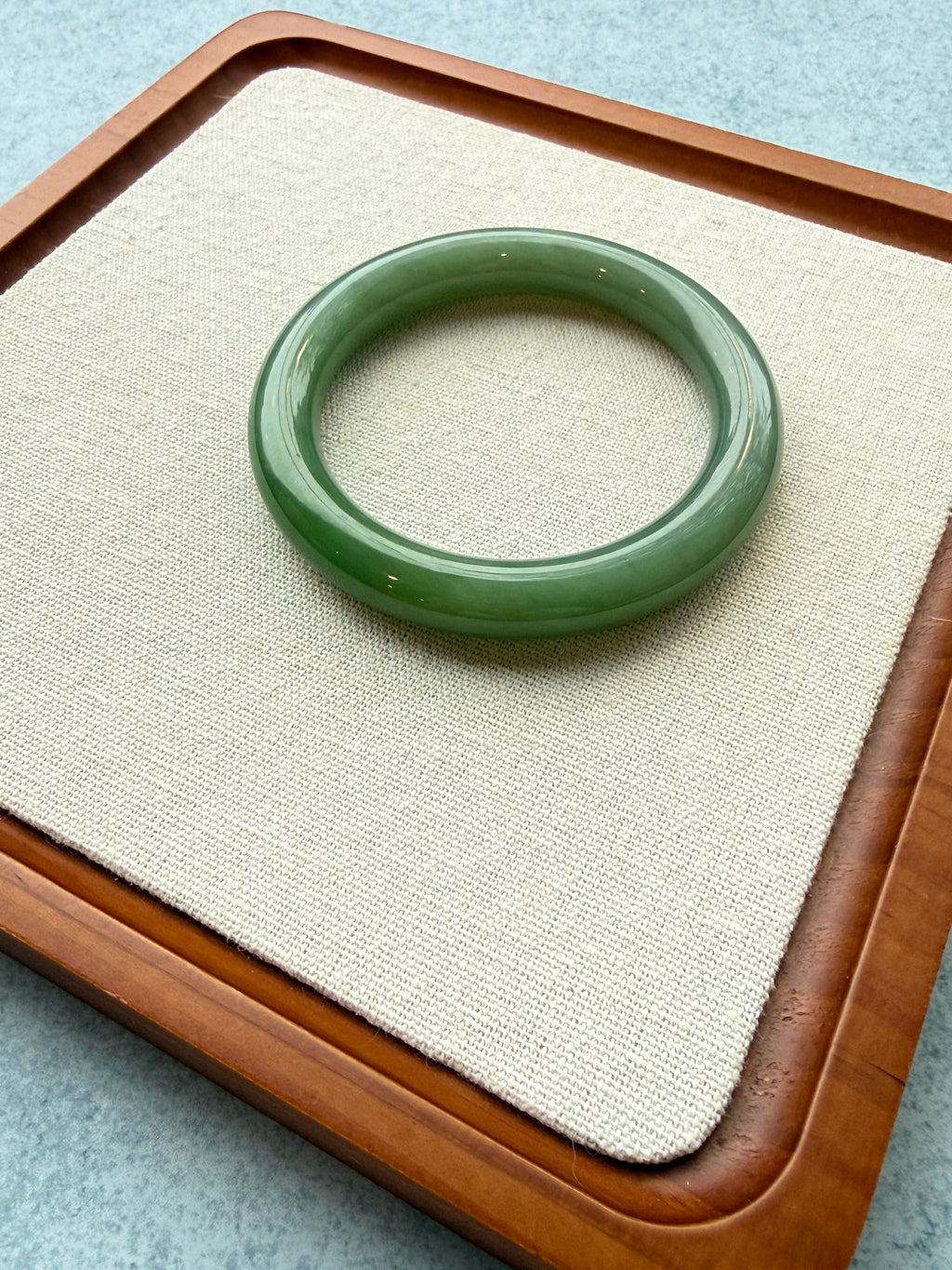 Green jadeite bangle on a beige tray