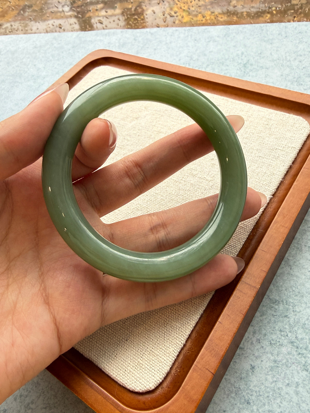 Green jadeite bangle in hand, side view