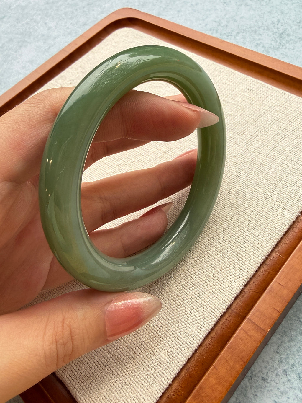 Green jadeite bangle held up to the light