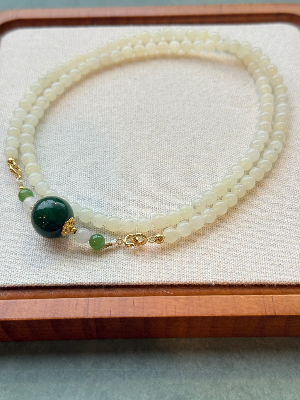 White hetian jade bead necklace with dark green center bead, laid flat