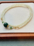 White hetian jade bead necklace with dark green center bead, laid flat