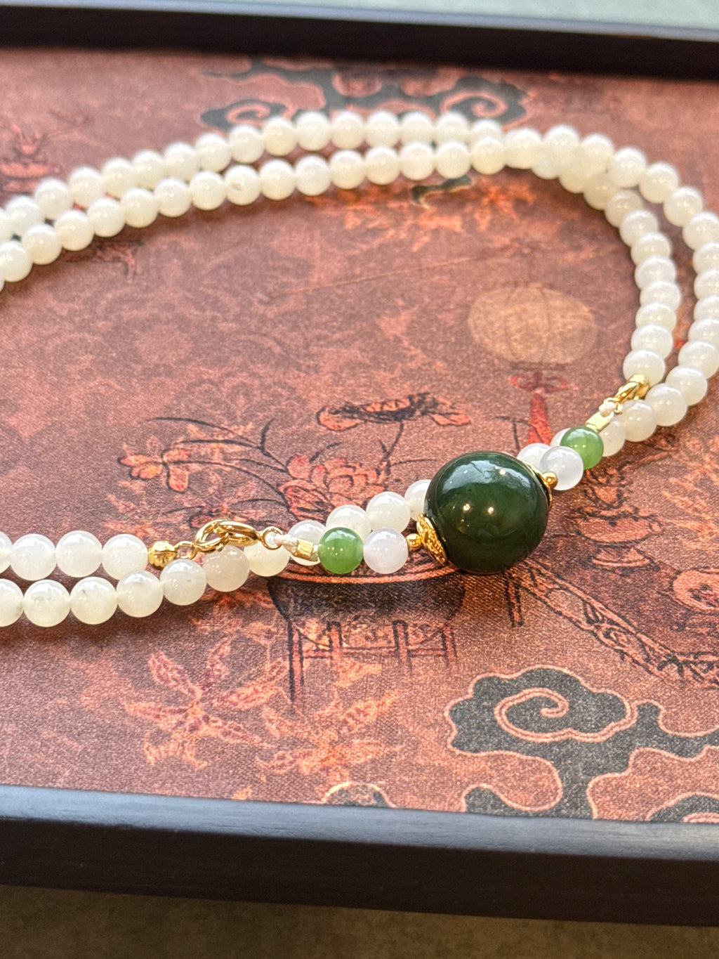 White hetian jade bead necklace with dark green center bead, close-up