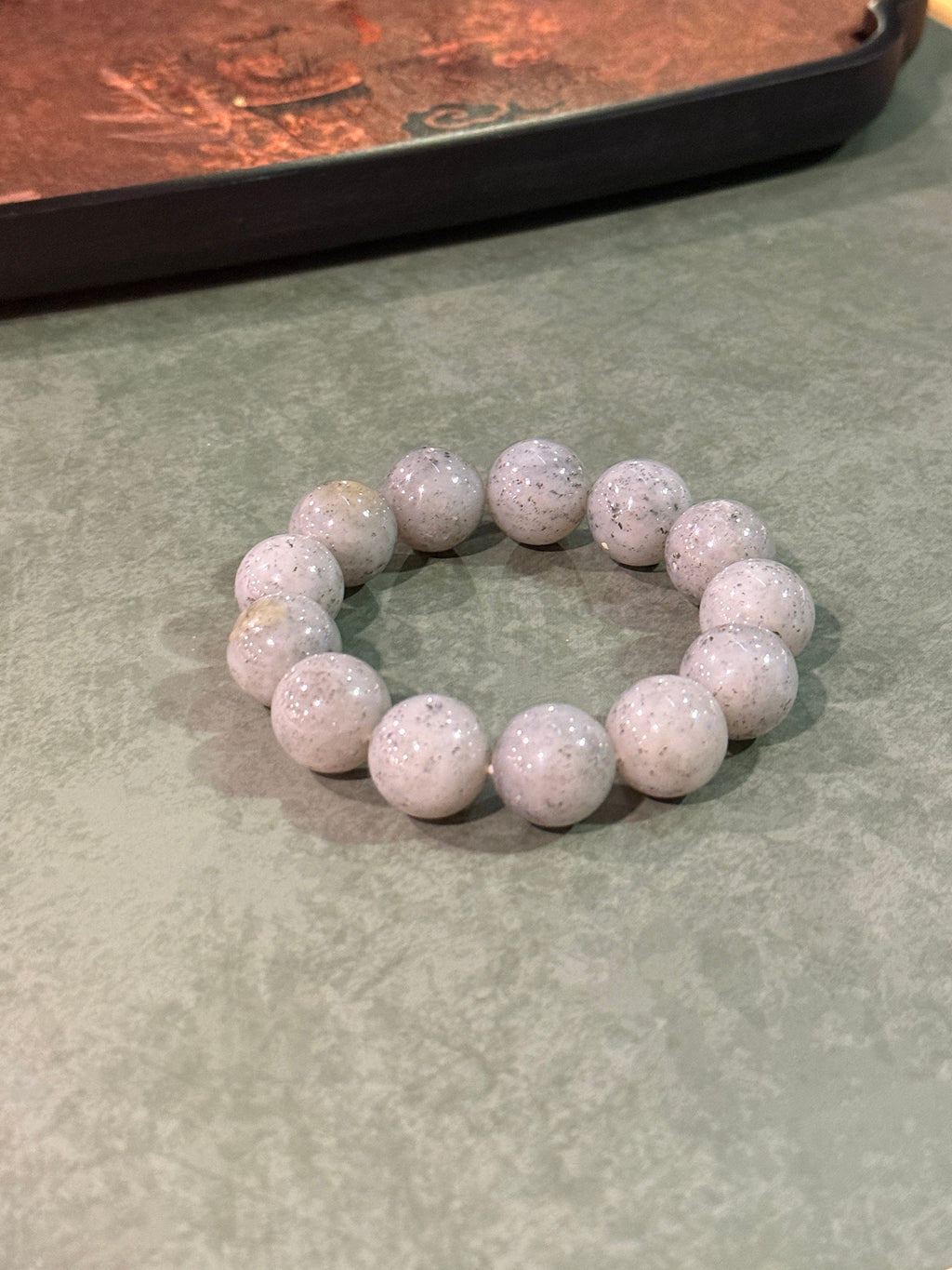 Grey jadeite bead bracelet with black speckles, laid flat