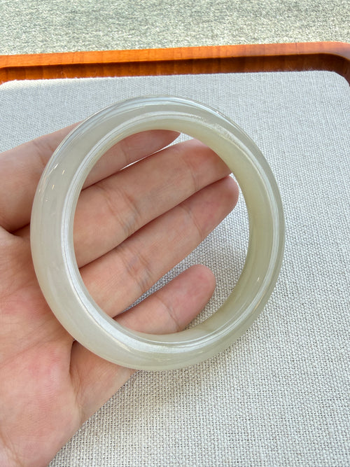 White hetian jade bangle held in hand showing its glow — CongCong Jade