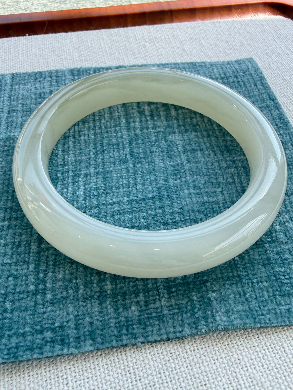 White hetian jade bangle on tray, side view — CongCong Jade