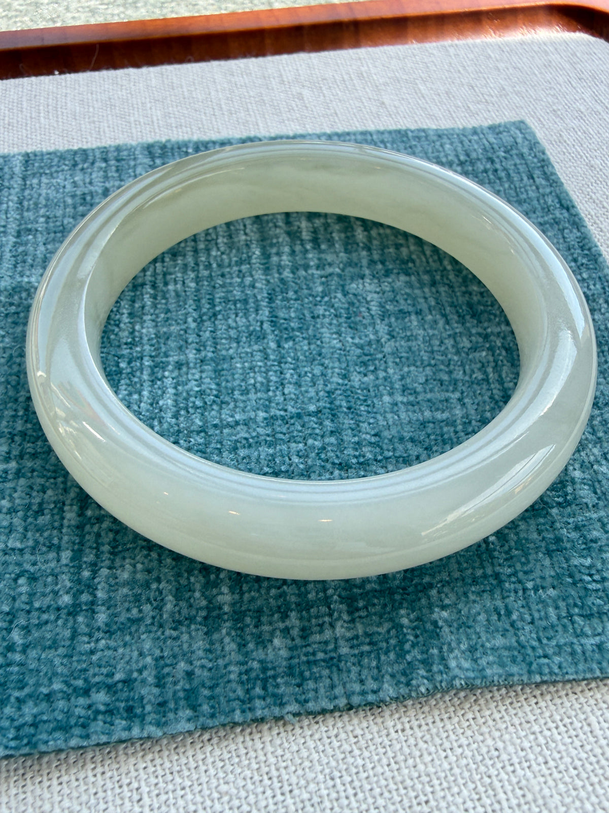 White hetian jade bangle on tray, side view — CongCong Jade