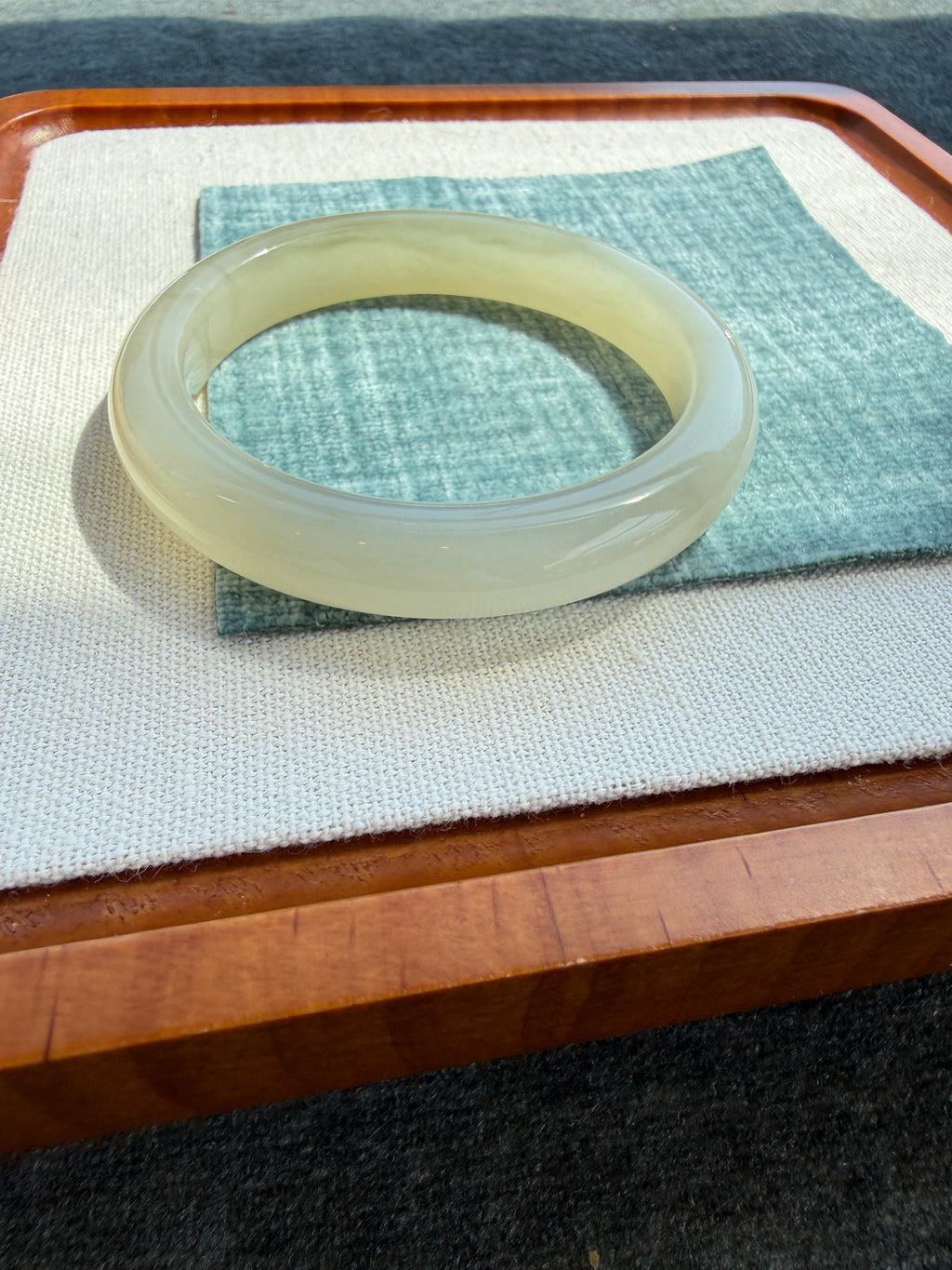 White hetian jade bangle held up to the light — CongCong Jade