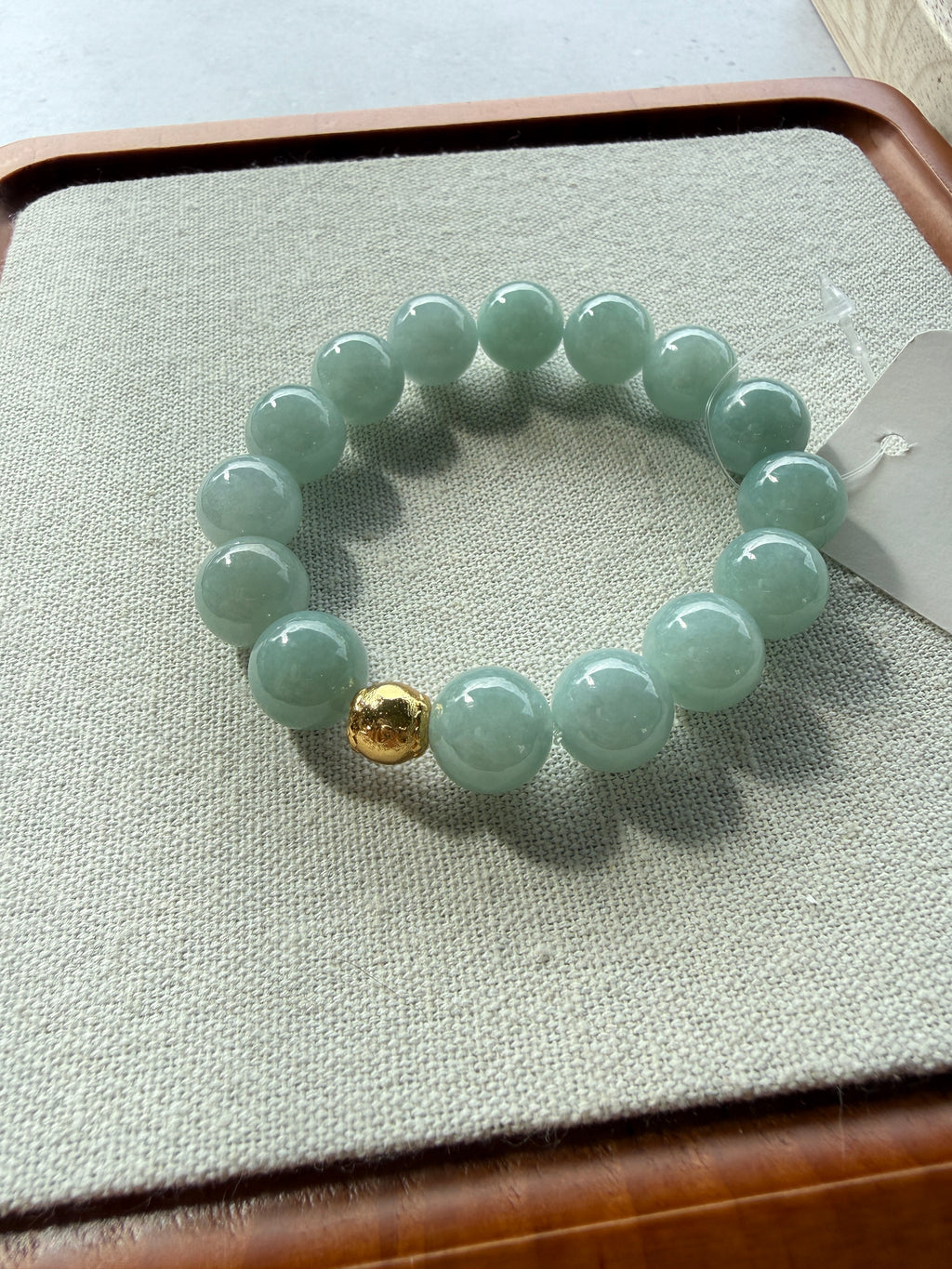 Light green jadeite bead bracelet with gold accent bead laid flat on tray — CongCong Jade