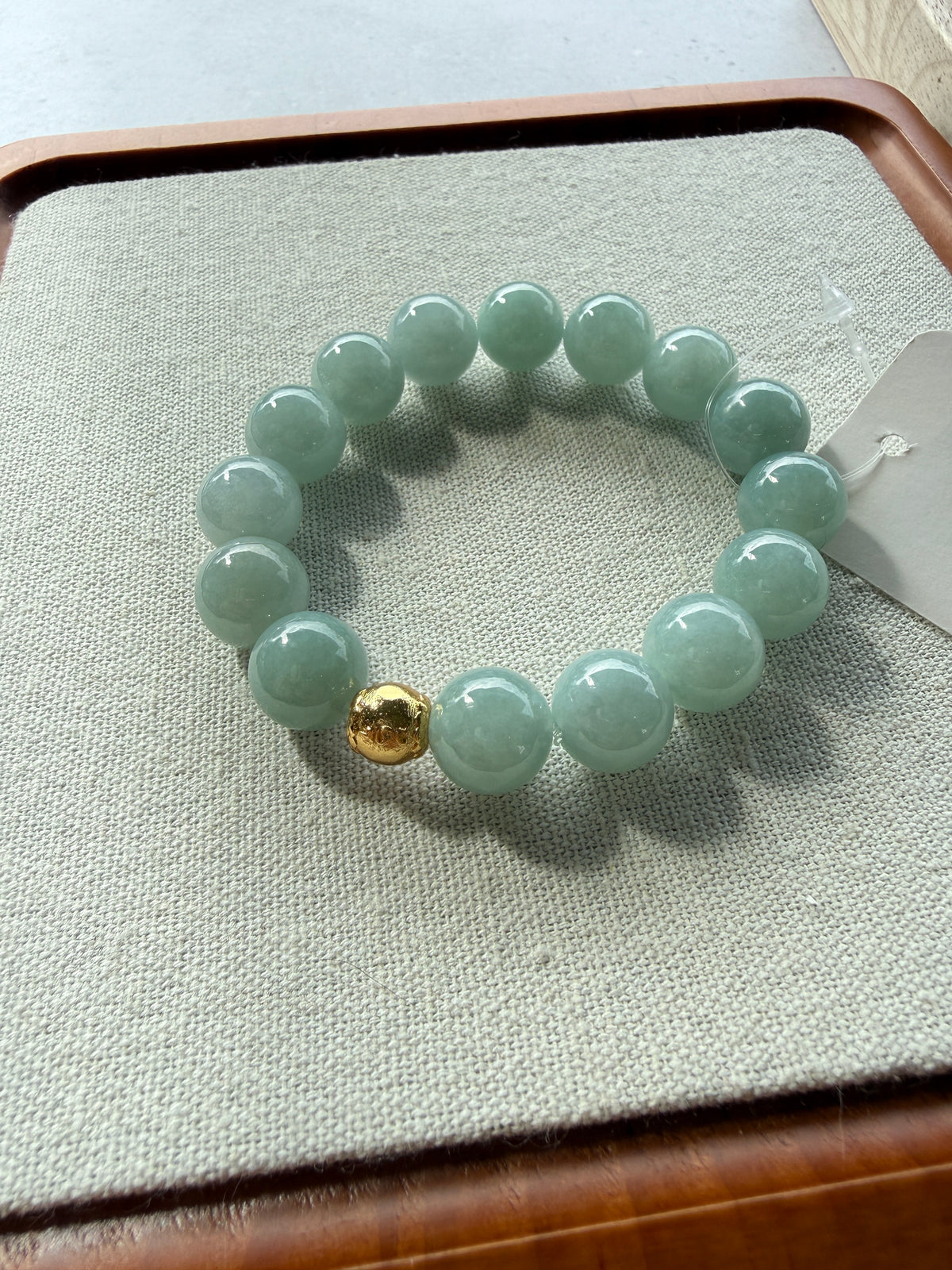 Light green jadeite bead bracelet with gold accent bead laid flat on tray — CongCong Jade