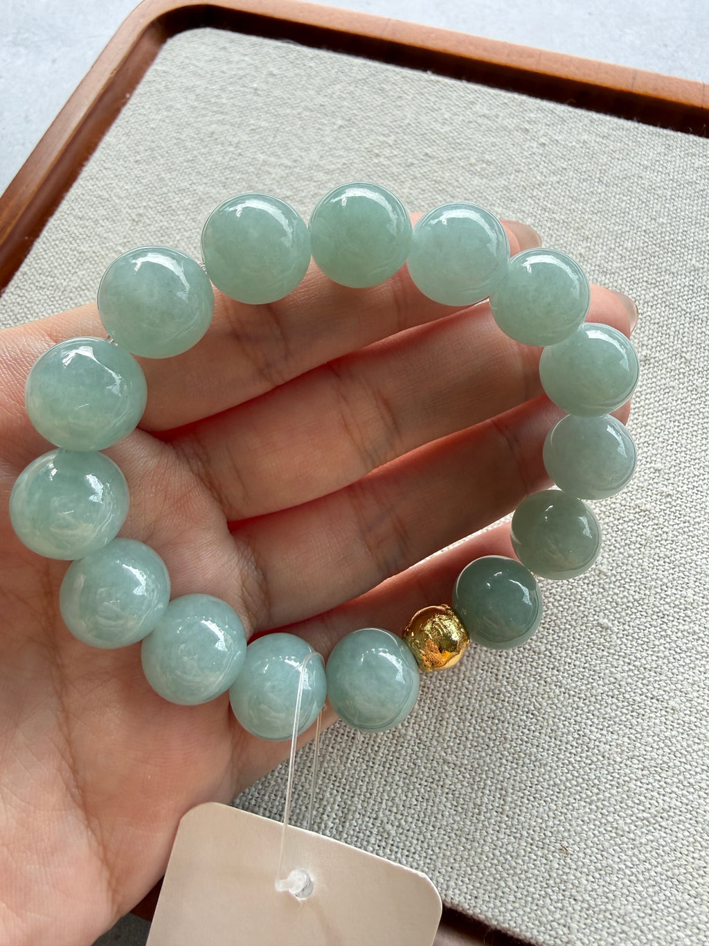 Light green jadeite bead bracelet held in hand — CongCong Jade