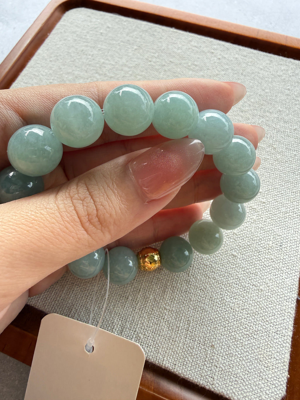Light green jadeite bead bracelet, close-up in hand — CongCong Jade