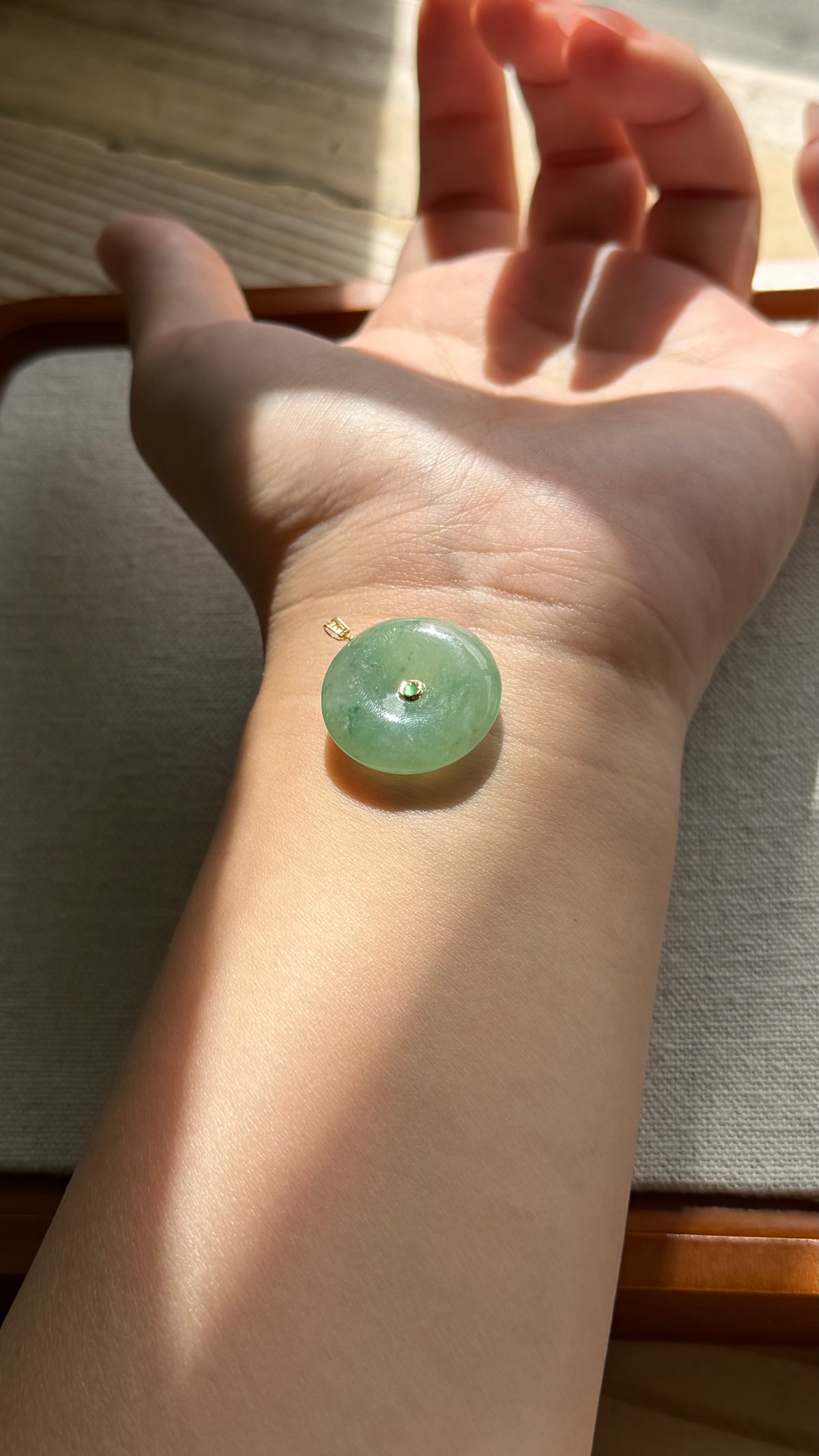 Green jadeite donut pendant worn on wrist for scale — CongCong Jade